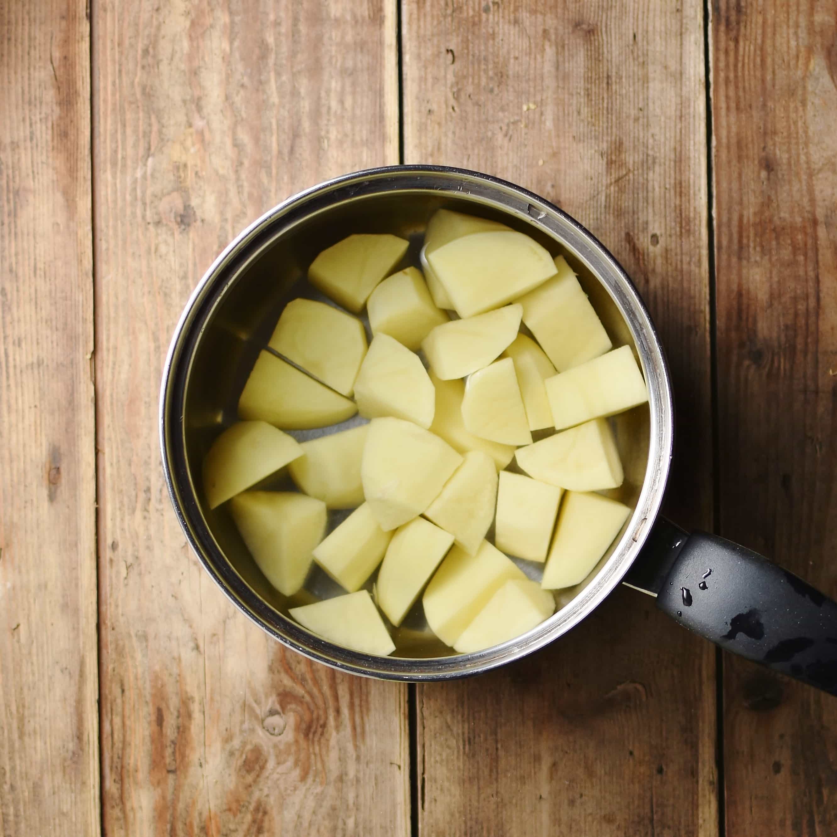 Cubed potatoes in water inside saucepan.