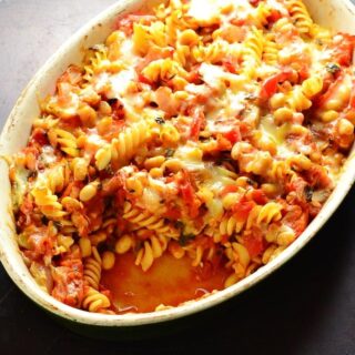 Top down view of bean pasta bake in oval casserole dish on oven tray