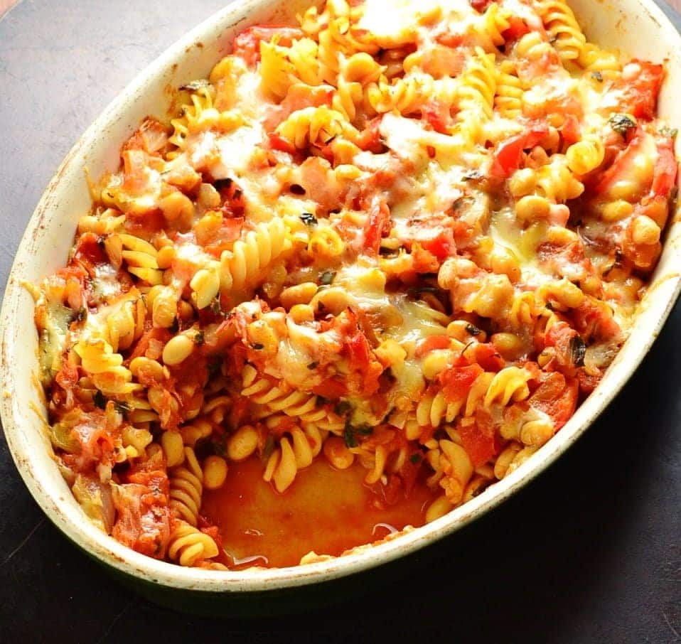 Top down view of bean pasta bake in oval casserole dish on oven tray