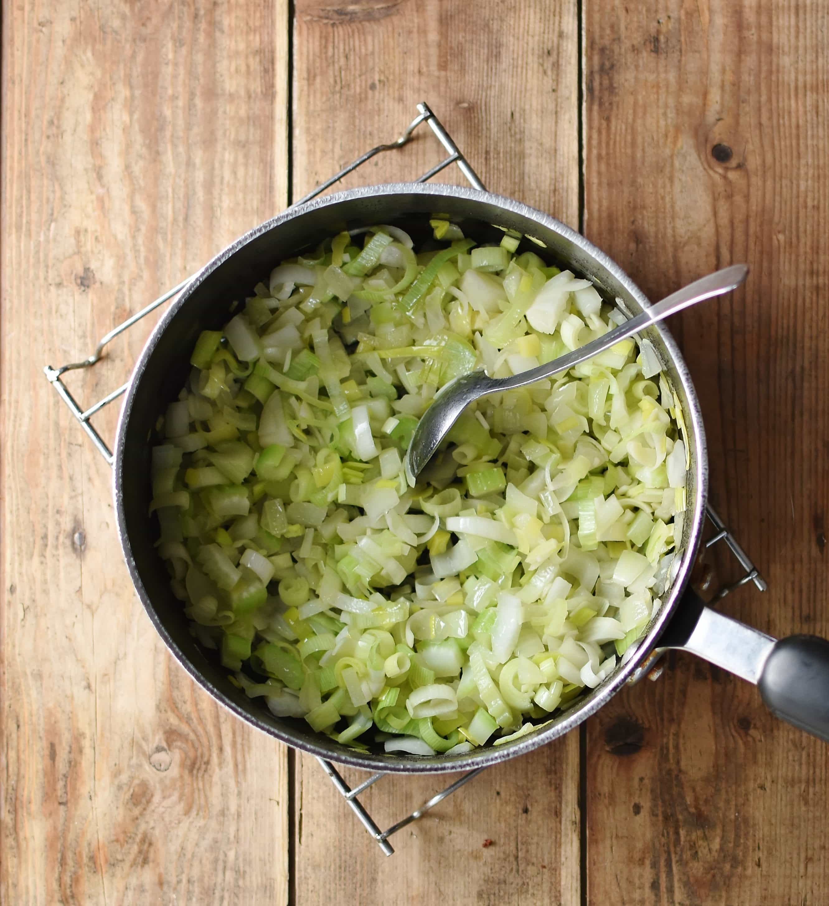 Chopped vegetables with spoon in large pot.