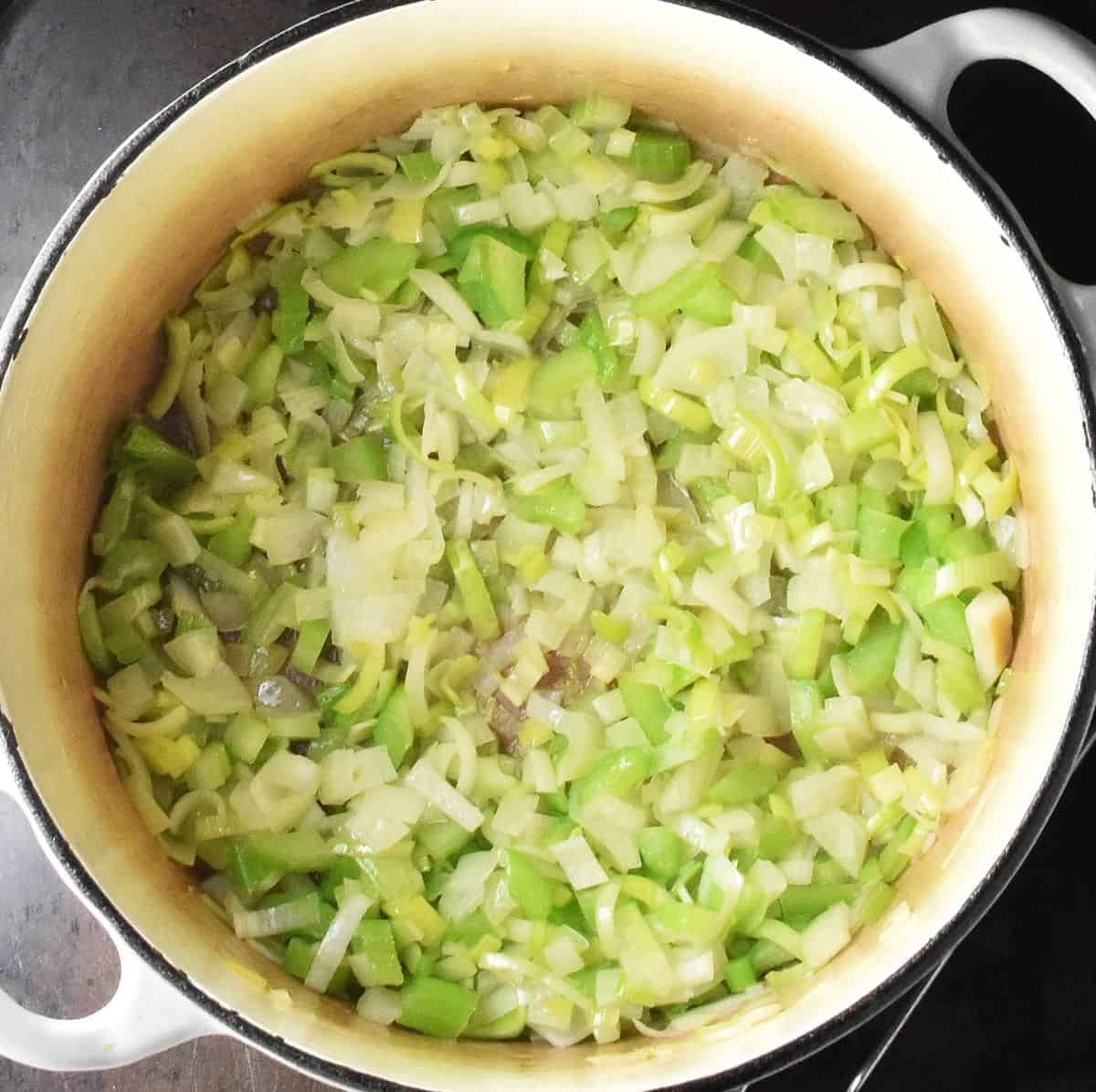 Finely chopped vegetables in bottom of large white pot.