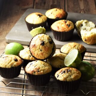 Chocolate chip muffins on rack and grey wooden board with limes.