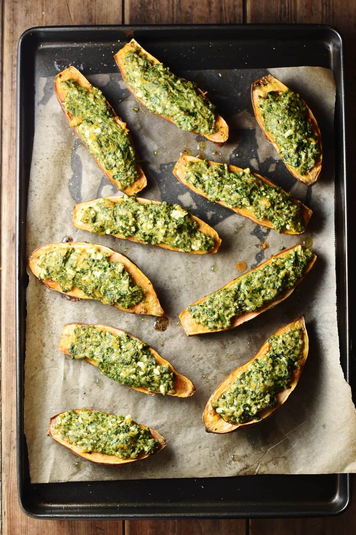 Spinach stuffed sweet potatoes on top of baking sheet lined with paper.