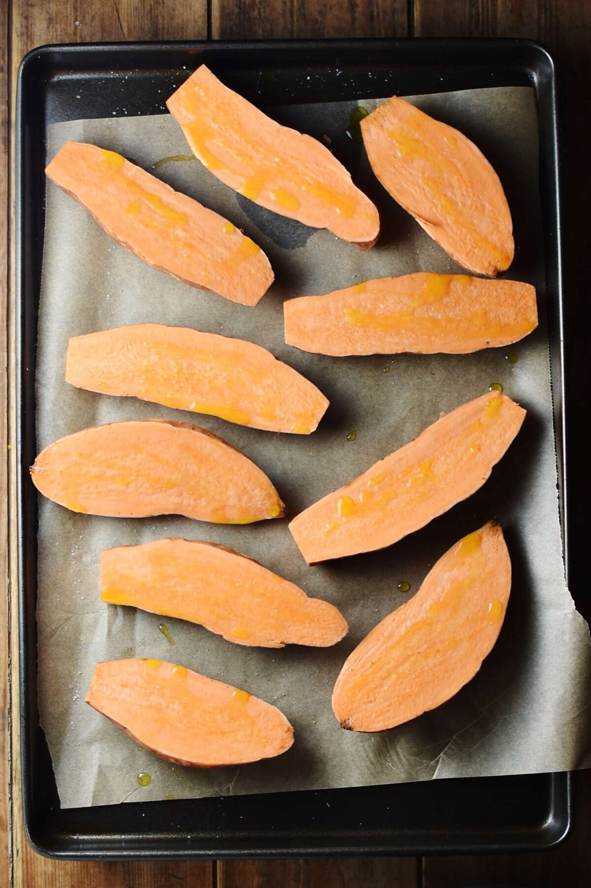 Sweet potato halves on top of tray lined with baking paper.