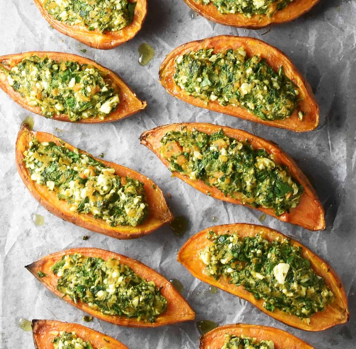 Top down view of baked sweet potato halves with spinach filling on parchment.