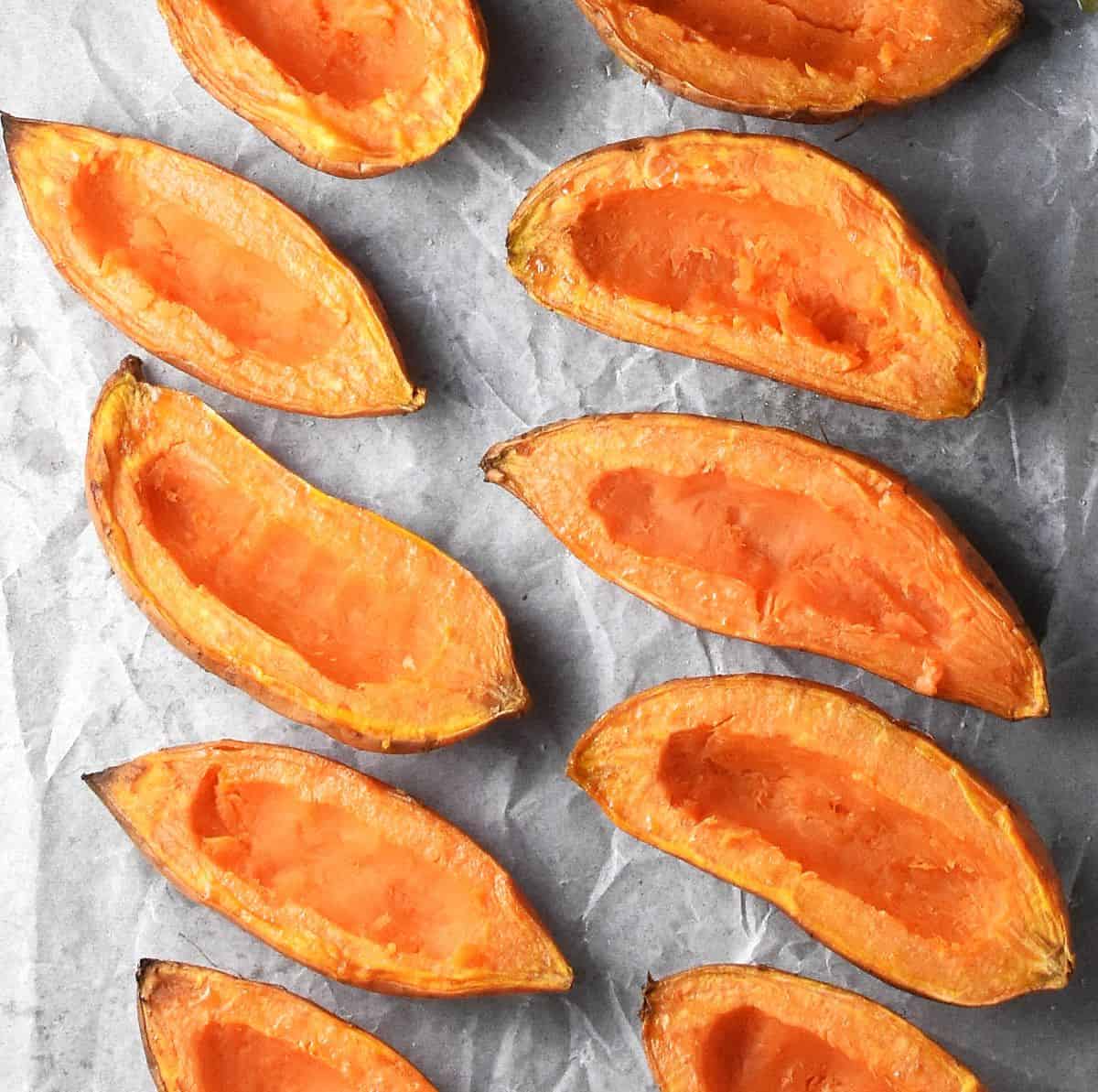 Top down view of hollowed out sweet potato halves on parchment.