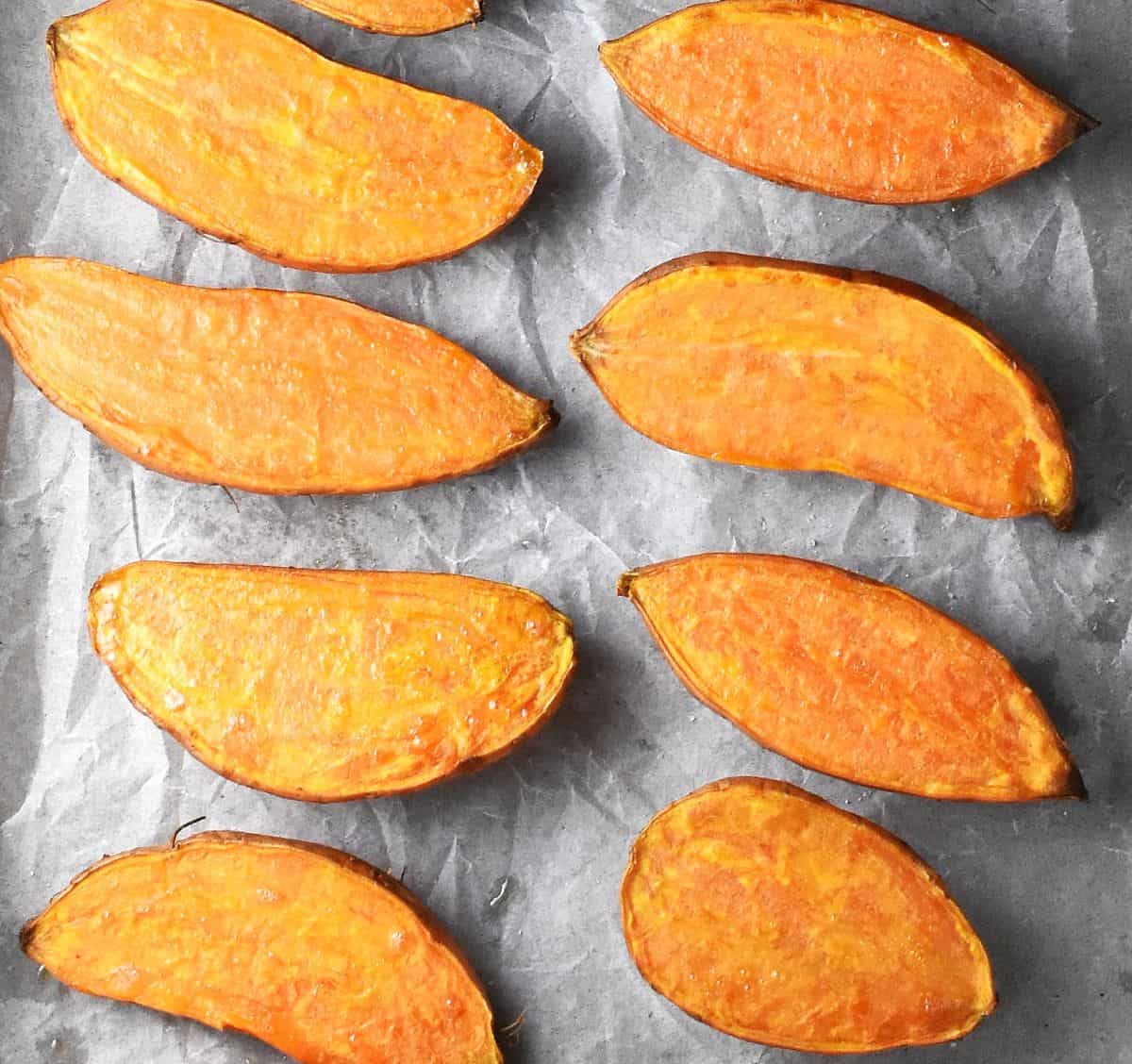 Roasted sweet potato halves on parchment paper.
