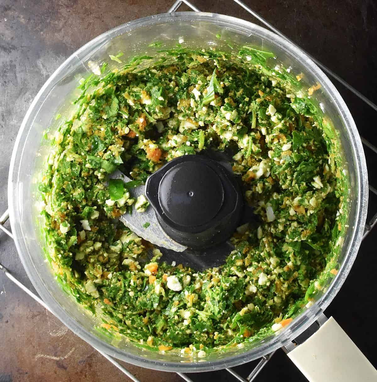 Top down view of spinach mixture in food processor bowl.