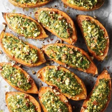 Top down view of baked spinach stuffed sweet potatoes on parchment paper.