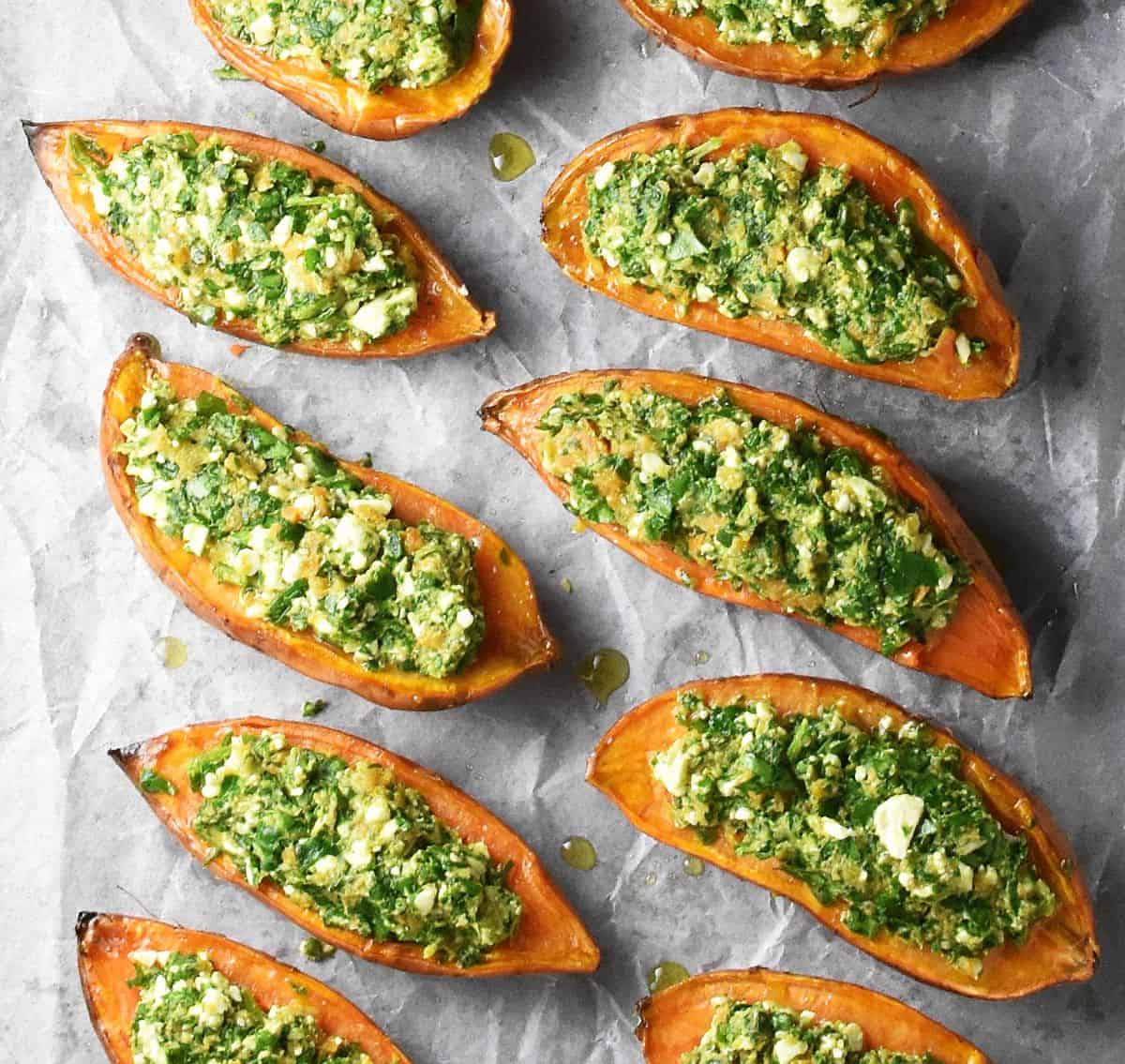 Sweet potato halves stuffed with spinach feta mixture on parchment paper.