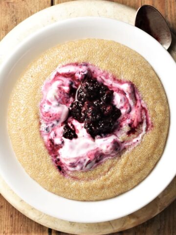Amaranth porridge with fruit and yogurt in white bowl.