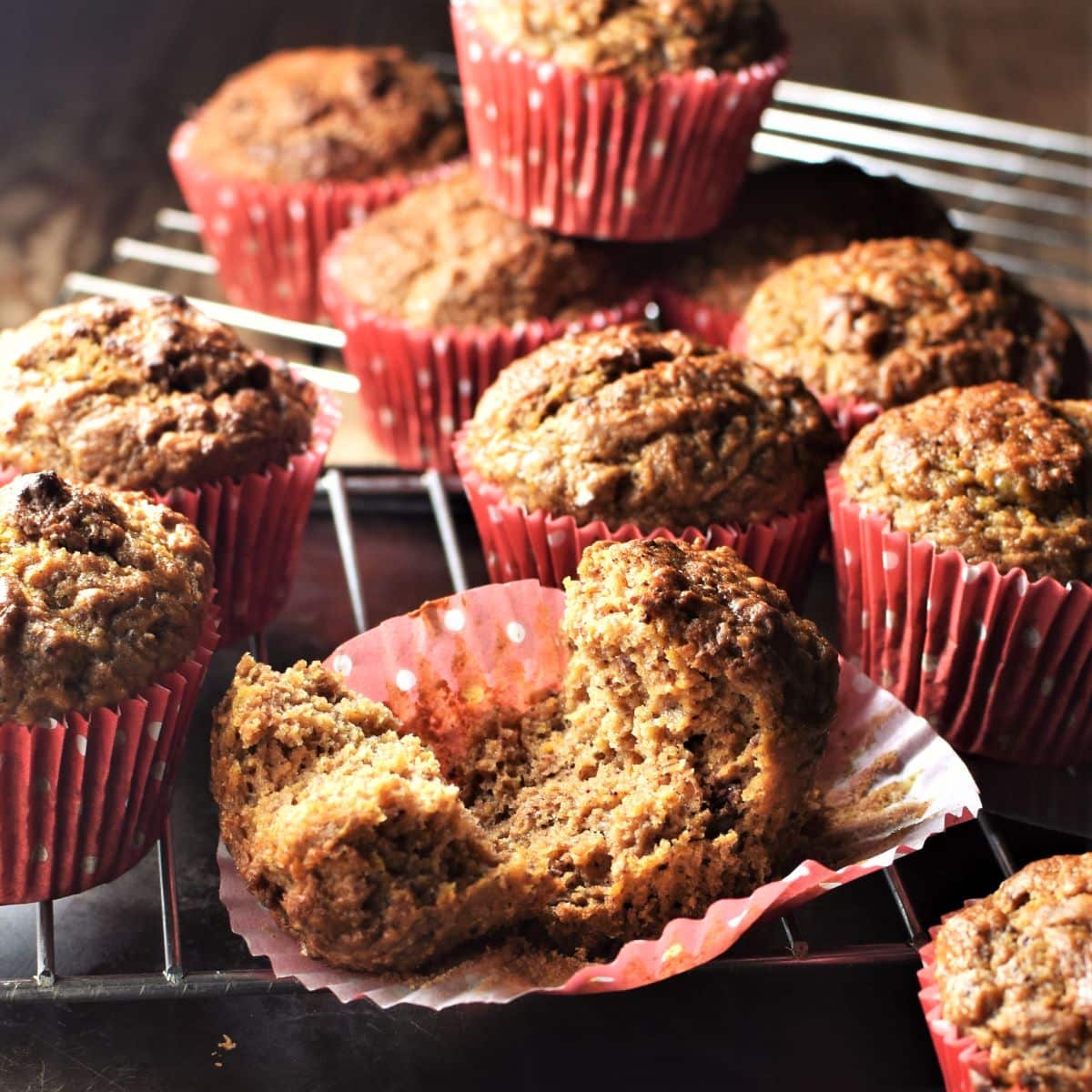 Side view of healthy carrot muffins in red liners on top of cooling rack.