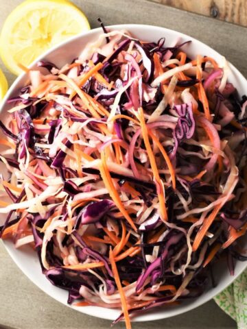 Top down view of no mayo coleslaw with lemon in background.