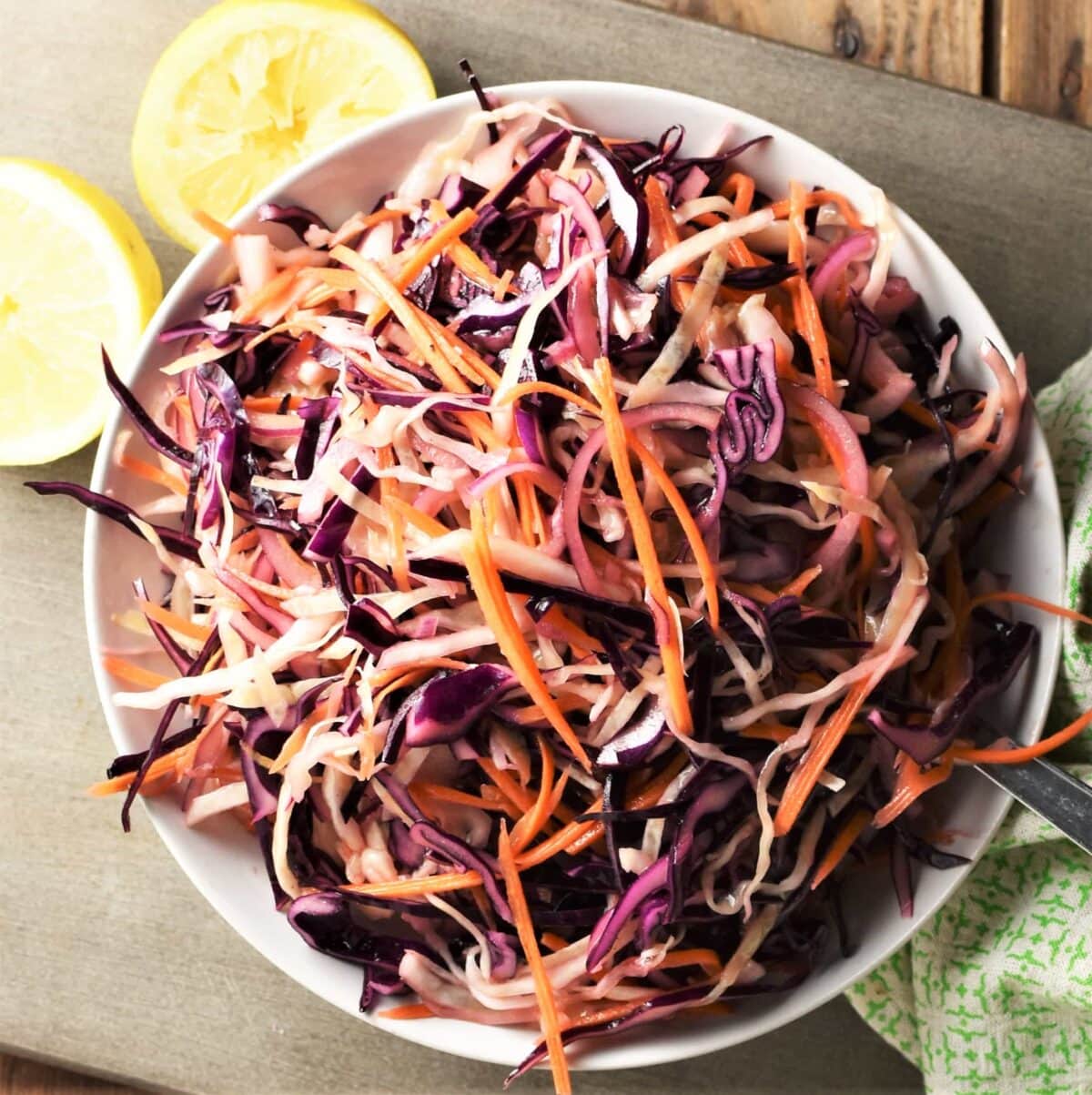 Top down view of no mayo coleslaw with lemon in background.