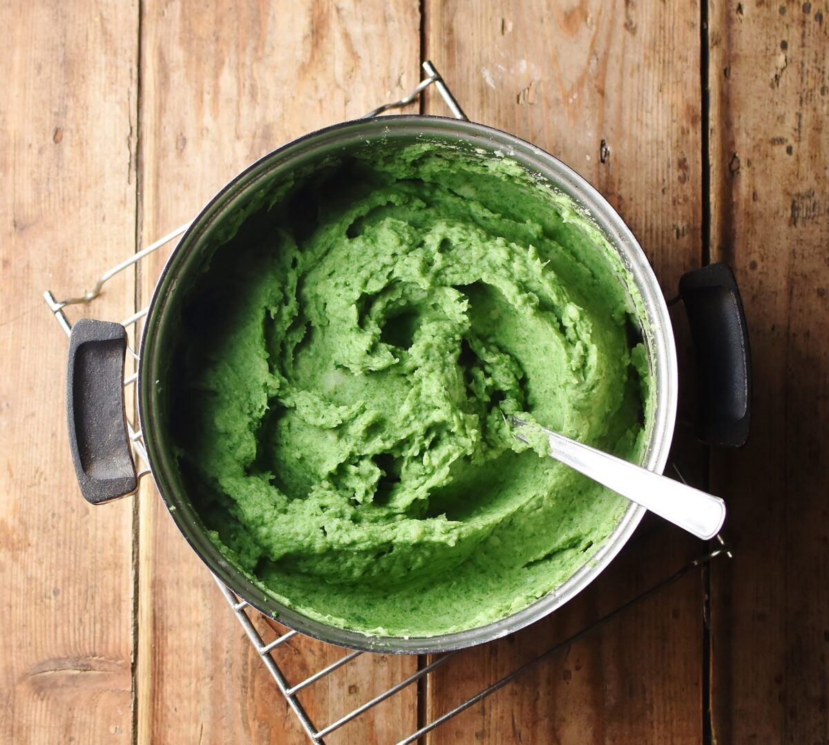 Spinach mashed potatoes in pot with spoon.