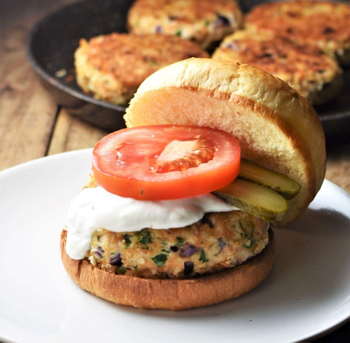 Side view of chicken burger with sauce and tomato slice.