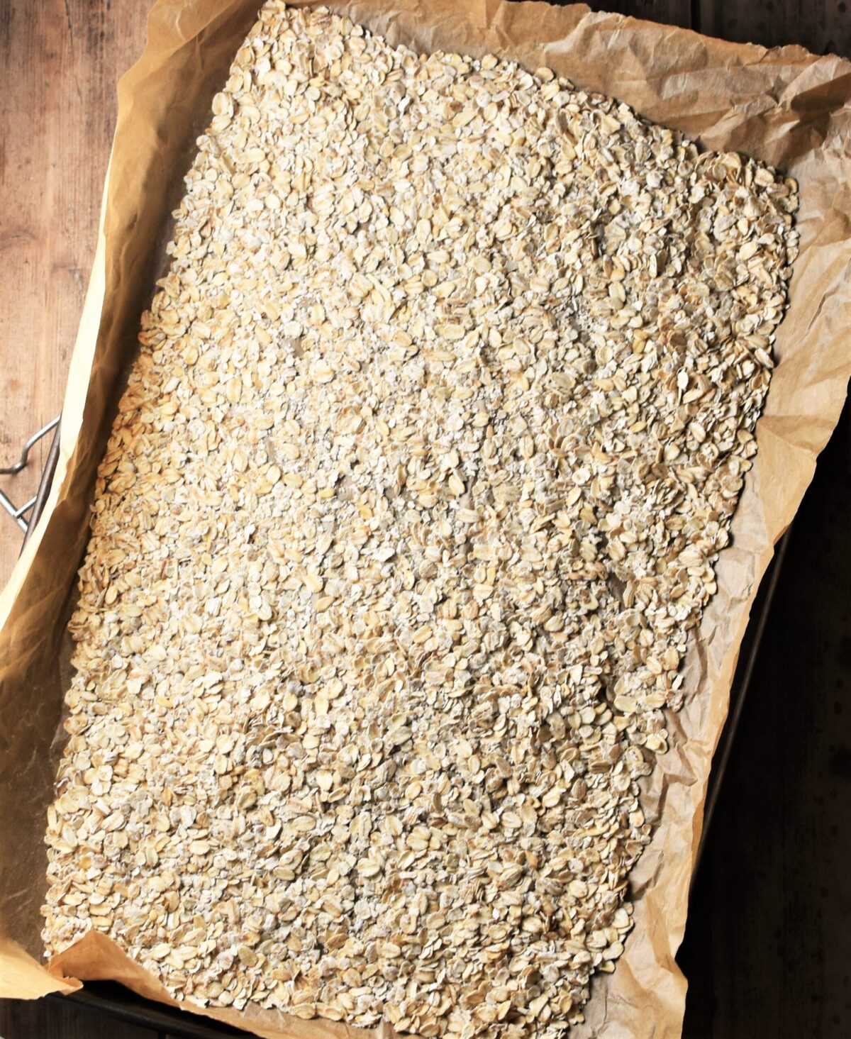 Oats spread over a baking sheet lined with parchment.