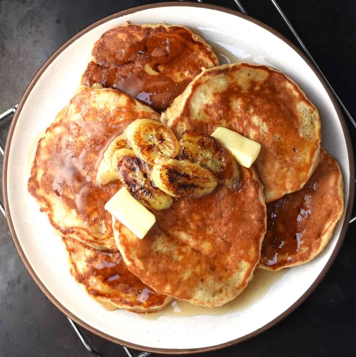 Top down view of banana yogurt pancakes with fried banana chunks on white plate.