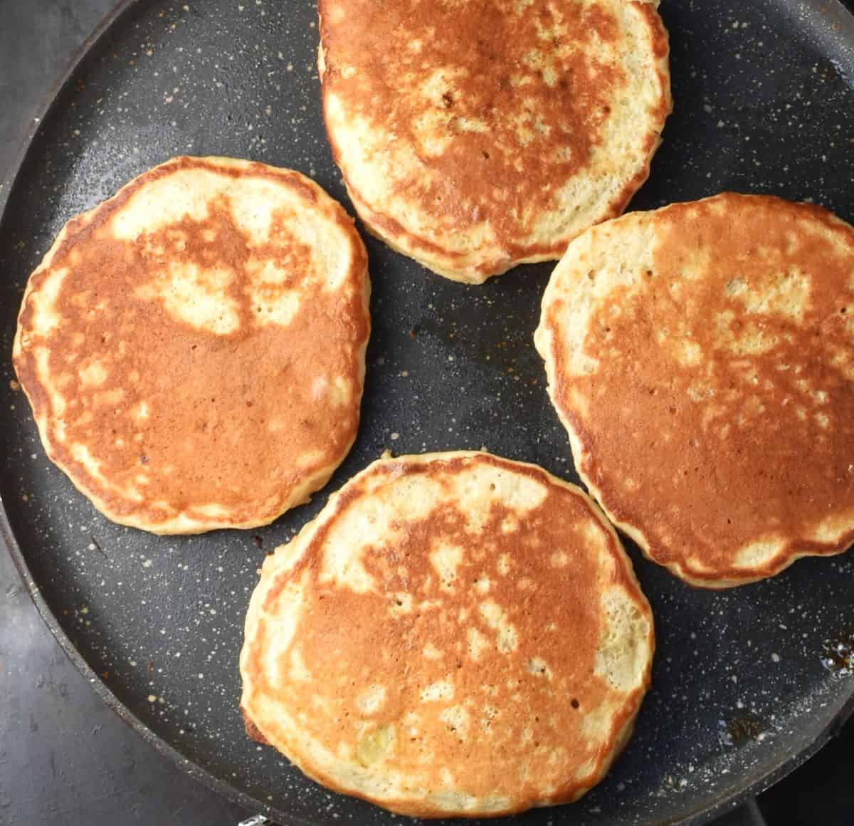 Top down view of 4 pancakes in flat pan.