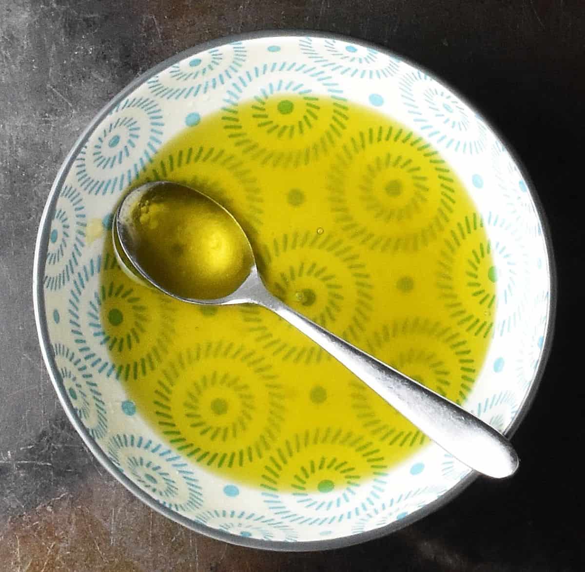 Top down view of dressing in blue bowl with small spoon.