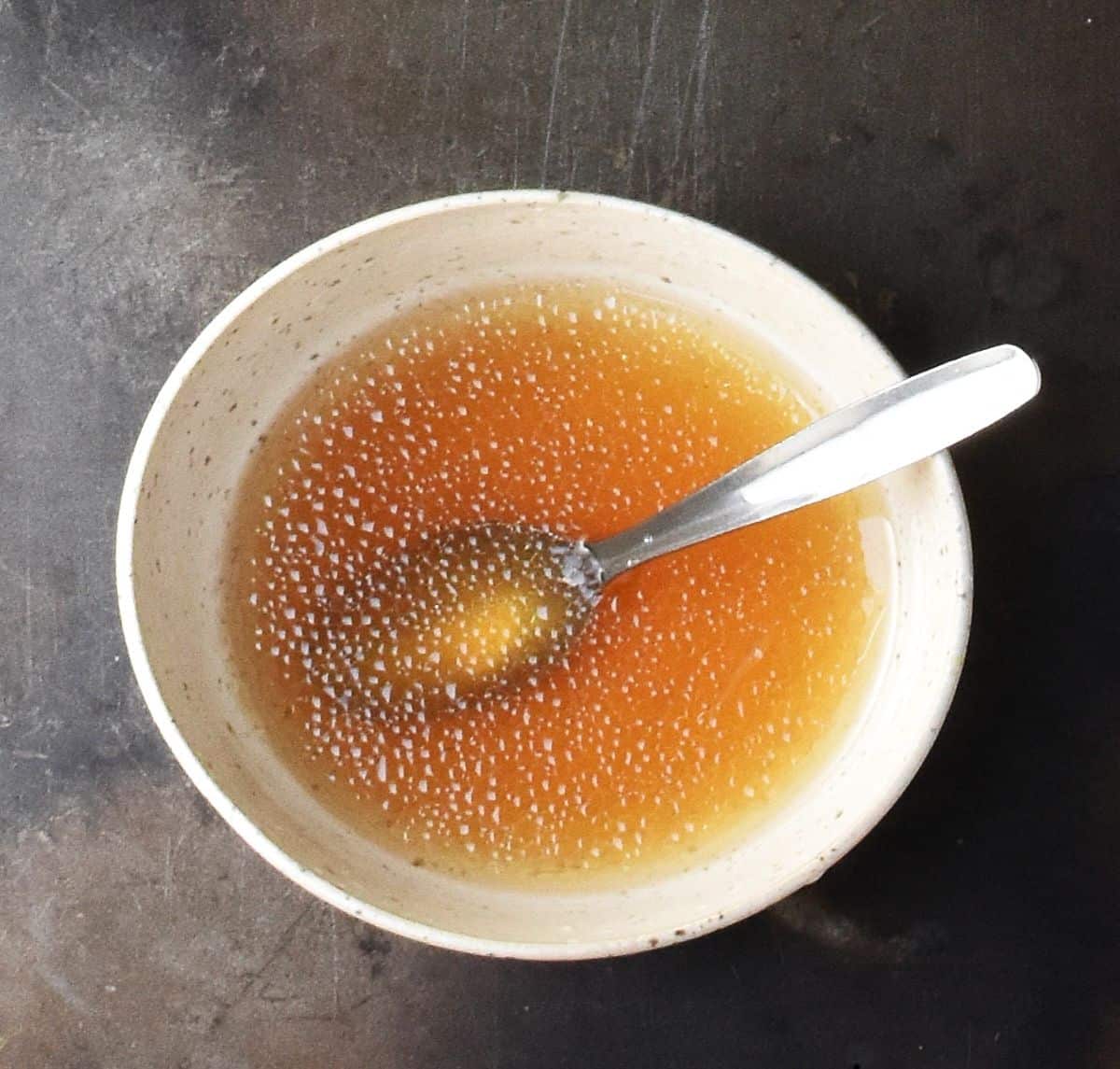 Grapefruit salad dressing in white bowl with spoon.