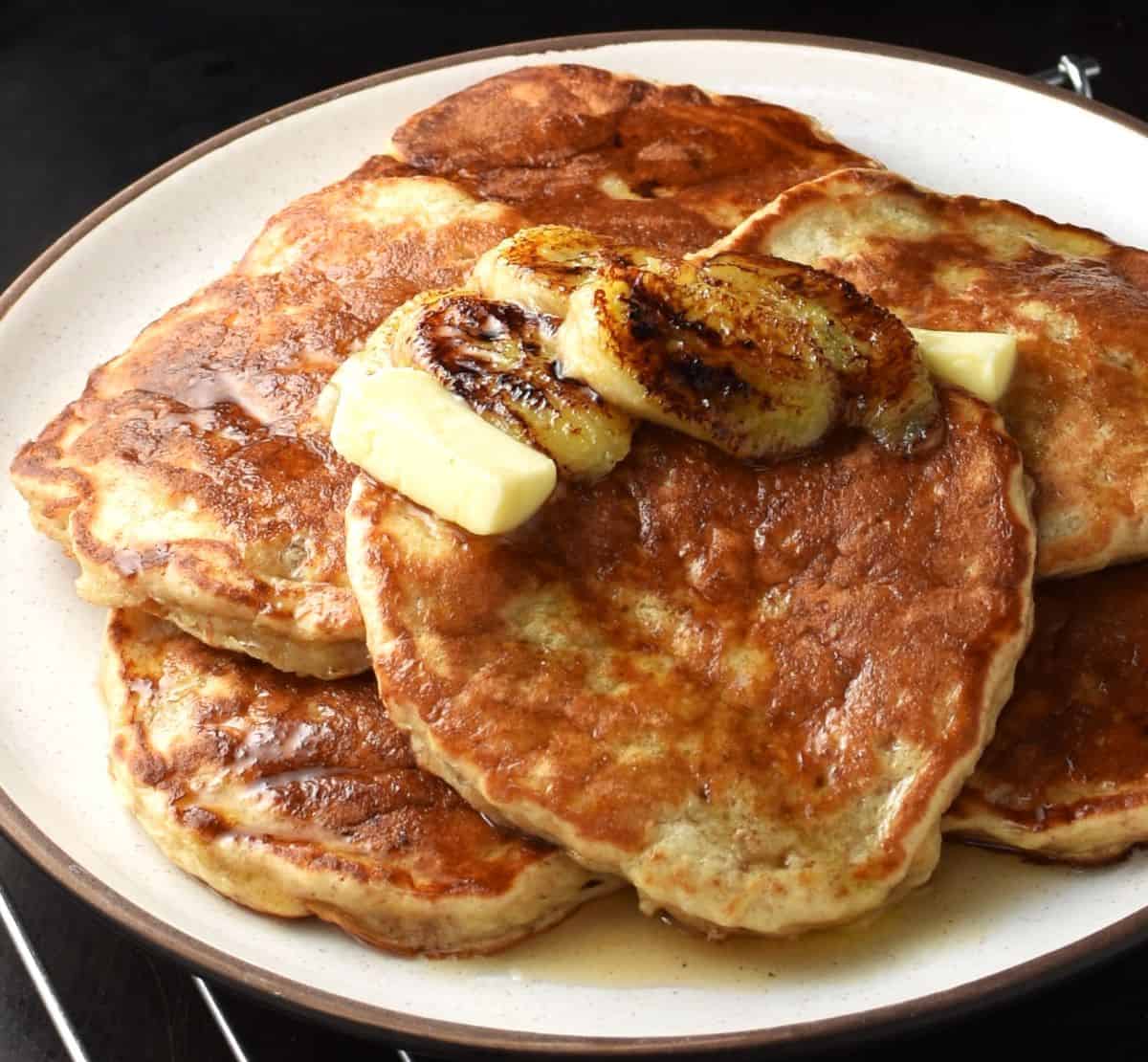 Side view of yogurt banana pancakes with knob of butter and maple syrup.