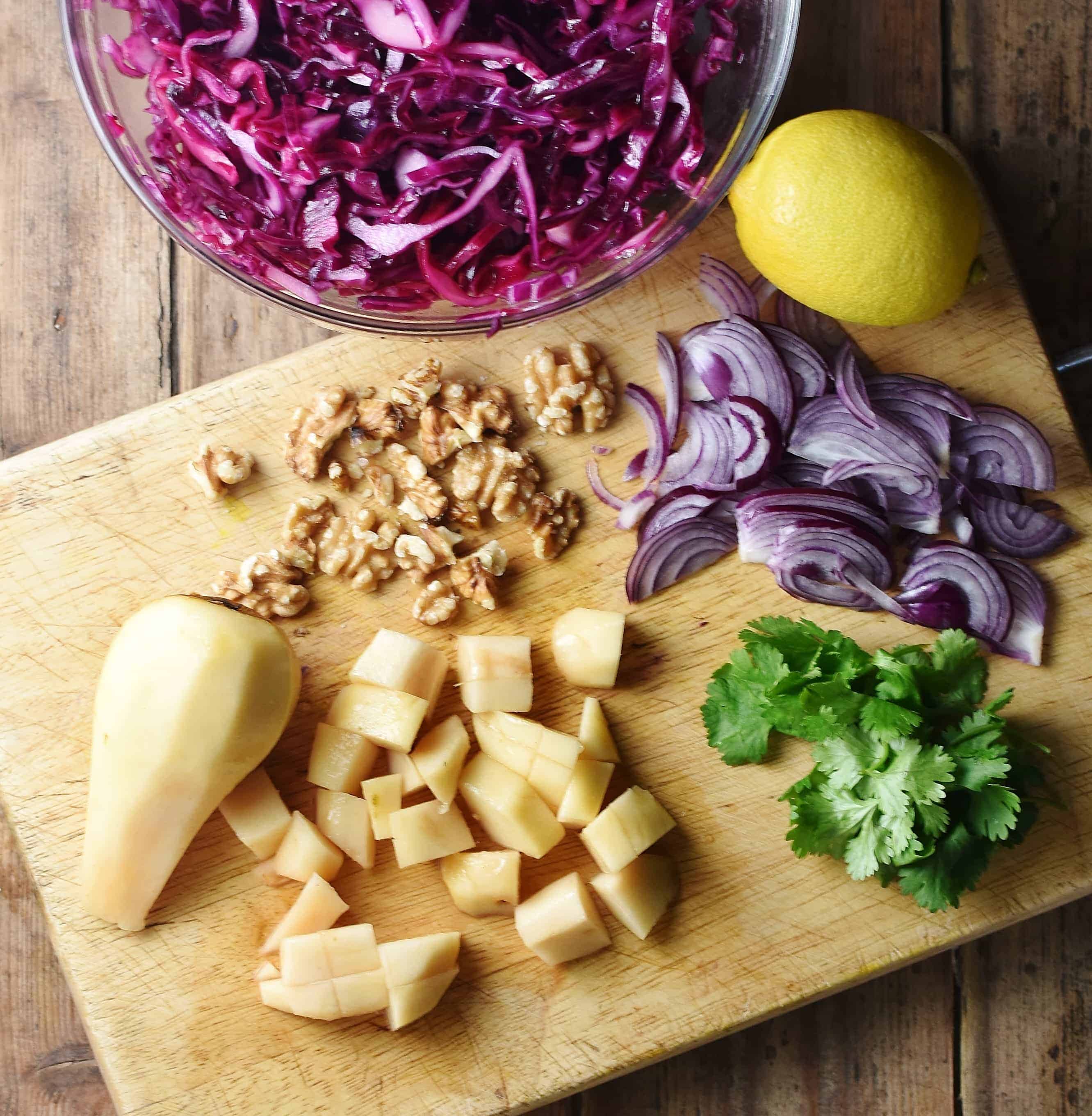 Peeled, chopped pear, cilantro, walnuts, sliced red onion, lemon and red cabbage slaw in bowl at the top.