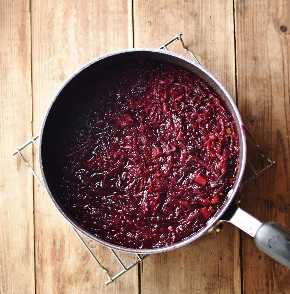 Grated beets with water inside pot on top of cooling rack.