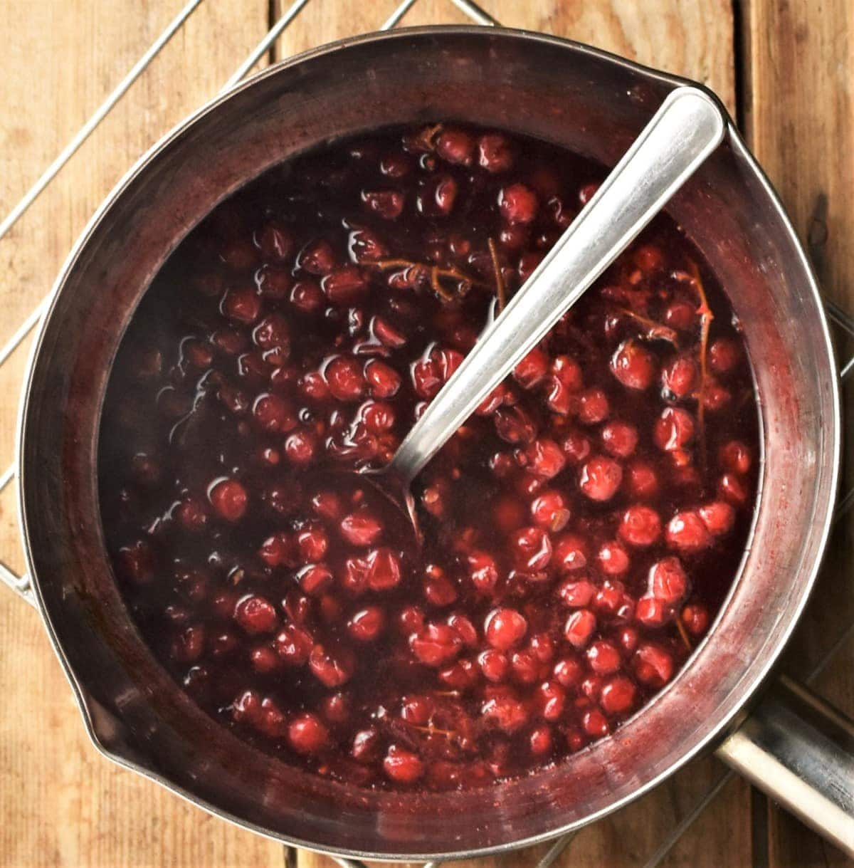 Redcurrants in sauce in pan with spoon.