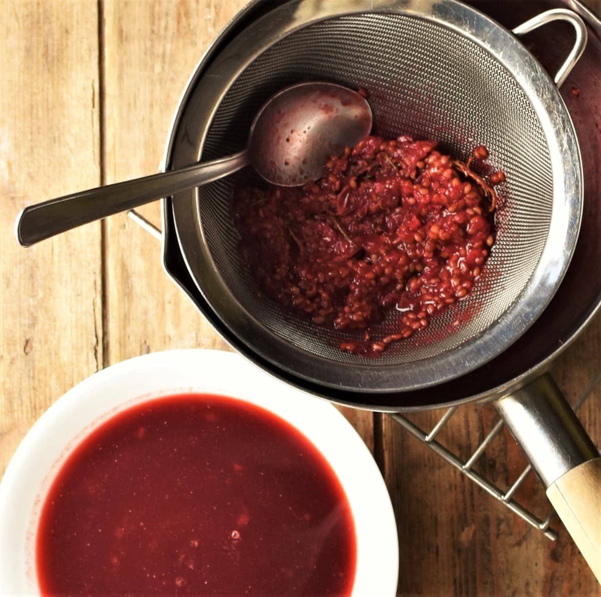 Redcurrant sauce and redcurrant pulp in sieve.