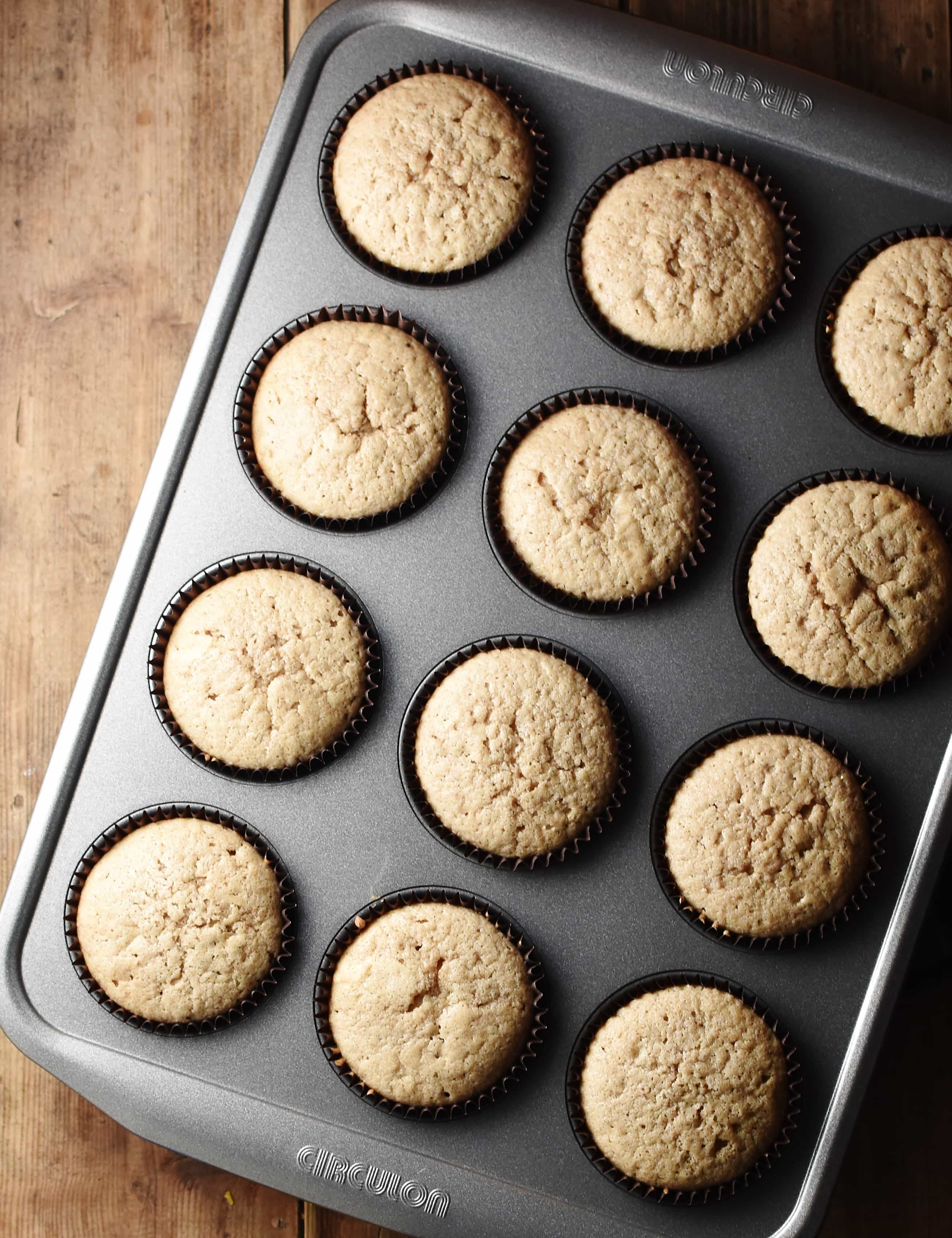 Cupcakes in brown cases in muffin pan.