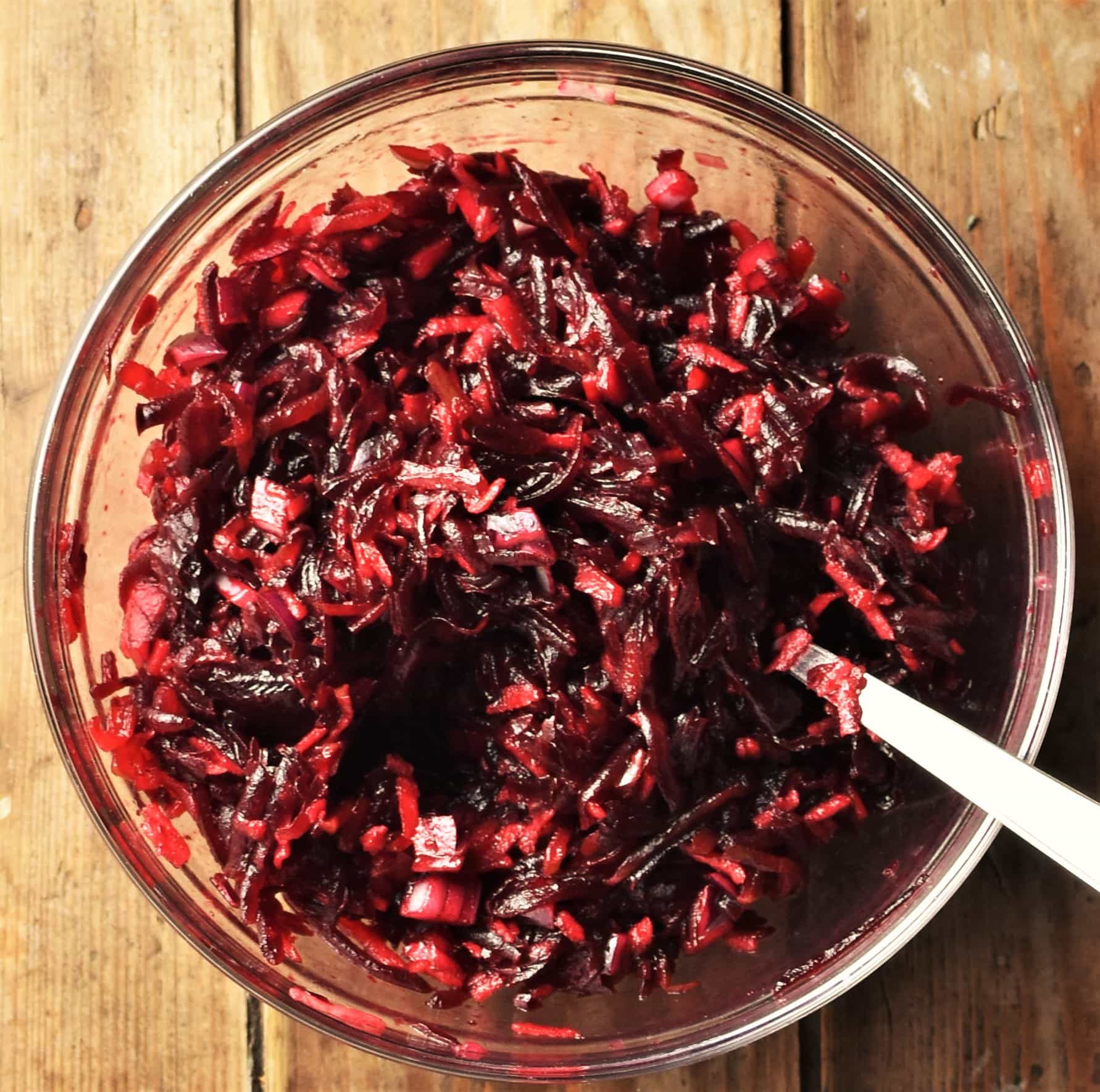 Beetroot slaw in mixing bowl with spoon.