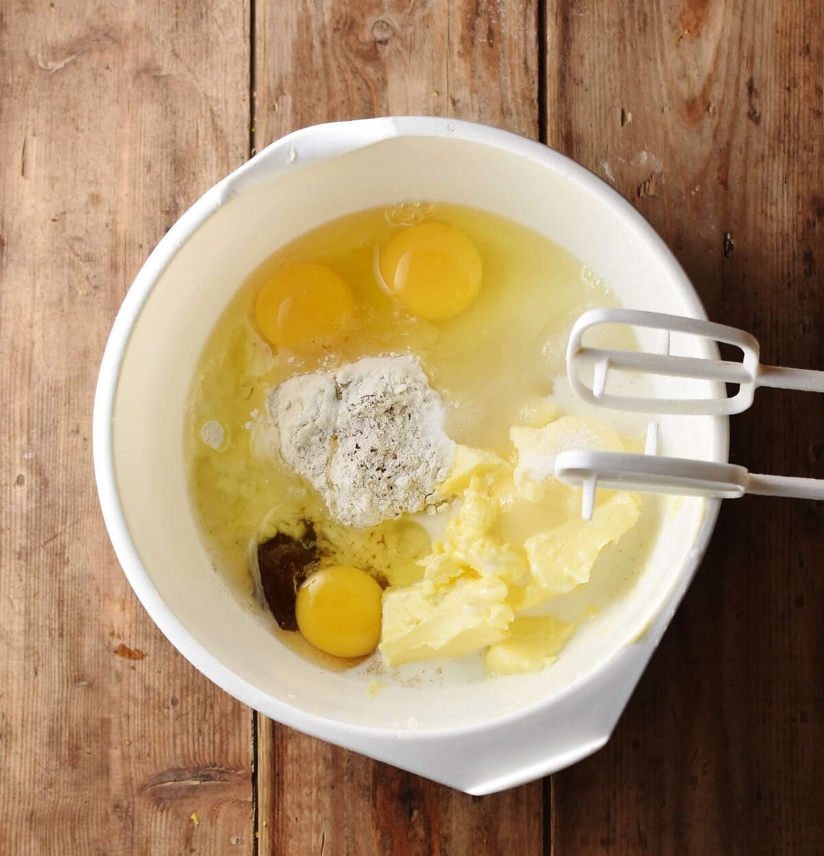 3 eggs, butter, spices, sugar and flour in large white bowl, with electric mixer ends.