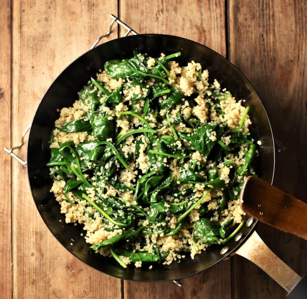 Wilted spinach and cooked quinoa in pan.