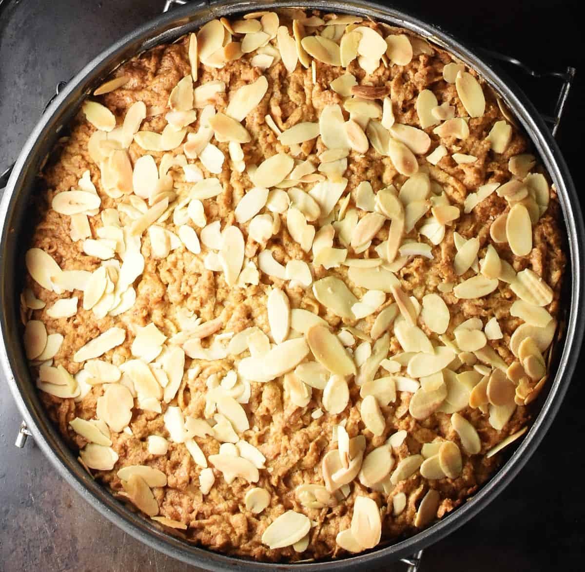 Baked cake with flaked almonds on top in pan.