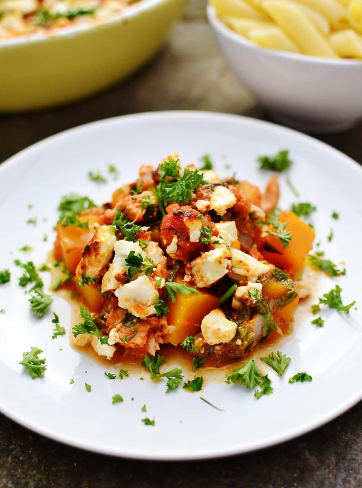 Easy tuna bake with butternut squash, spinach and feta and chopped herbs on white plate.