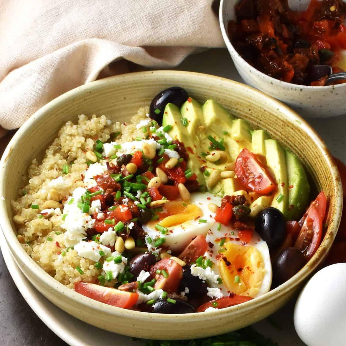 Side view of quinoa with egg and vegetables in brown bowl.
