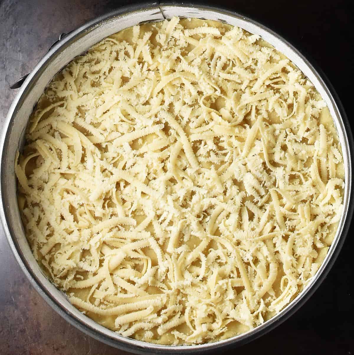 Top down view of shredded marzipan layer in round cake pan.