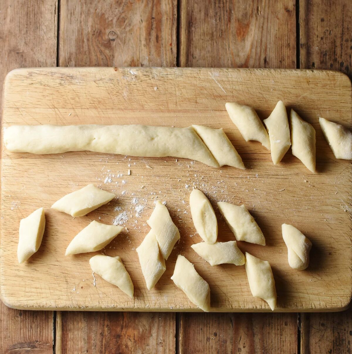 Kopytka dough shapes on top of wooden board.