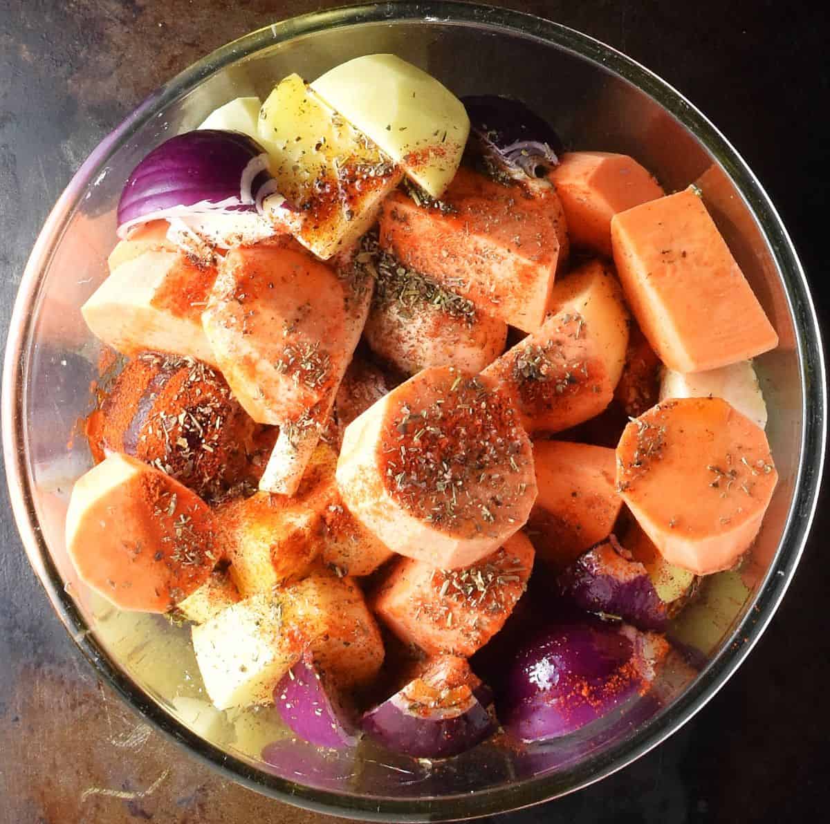 Pieces of peeled root vegetables with herbs in  glass bowl. 