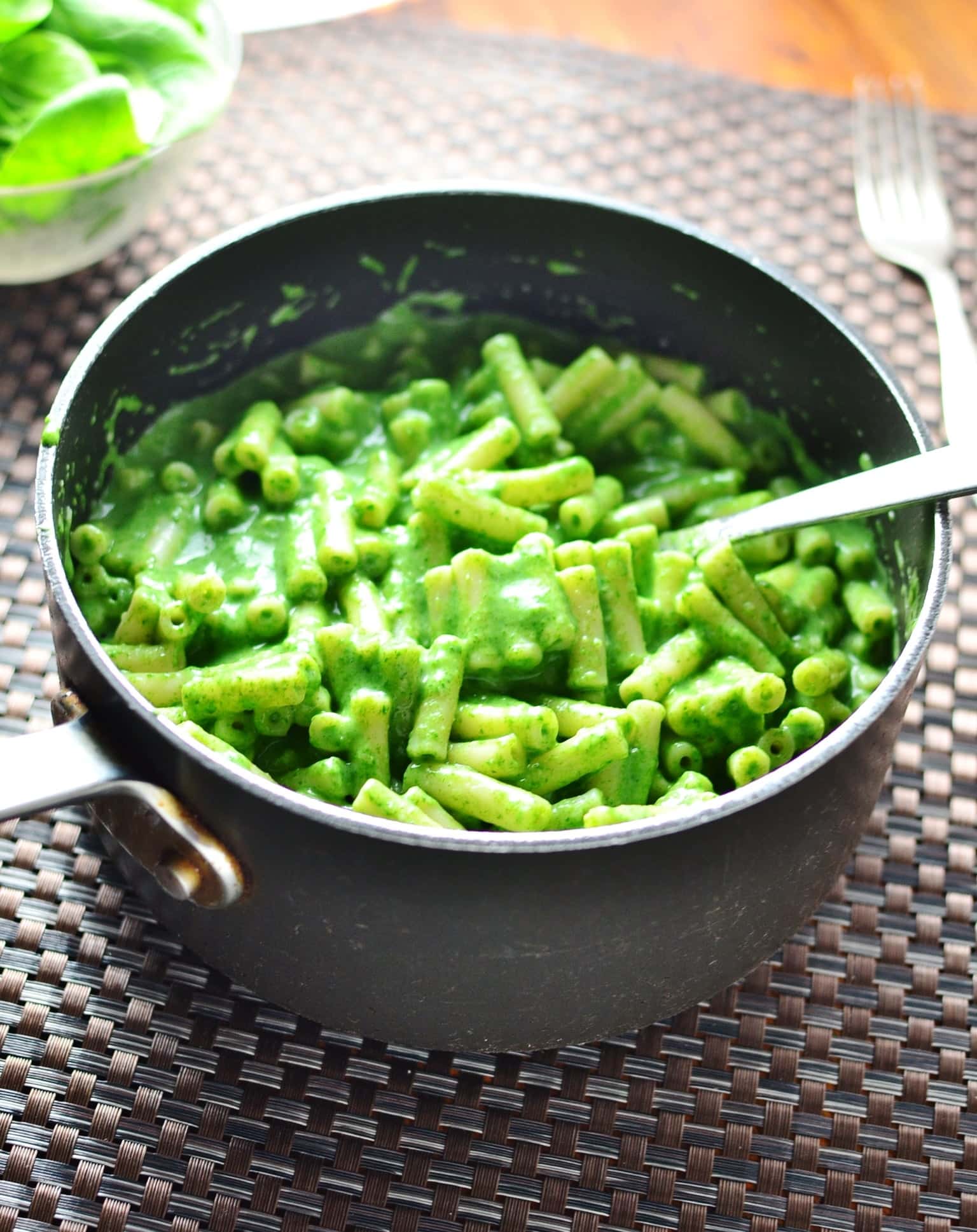 Macaroni in spinach sauce with spoon in large pot.