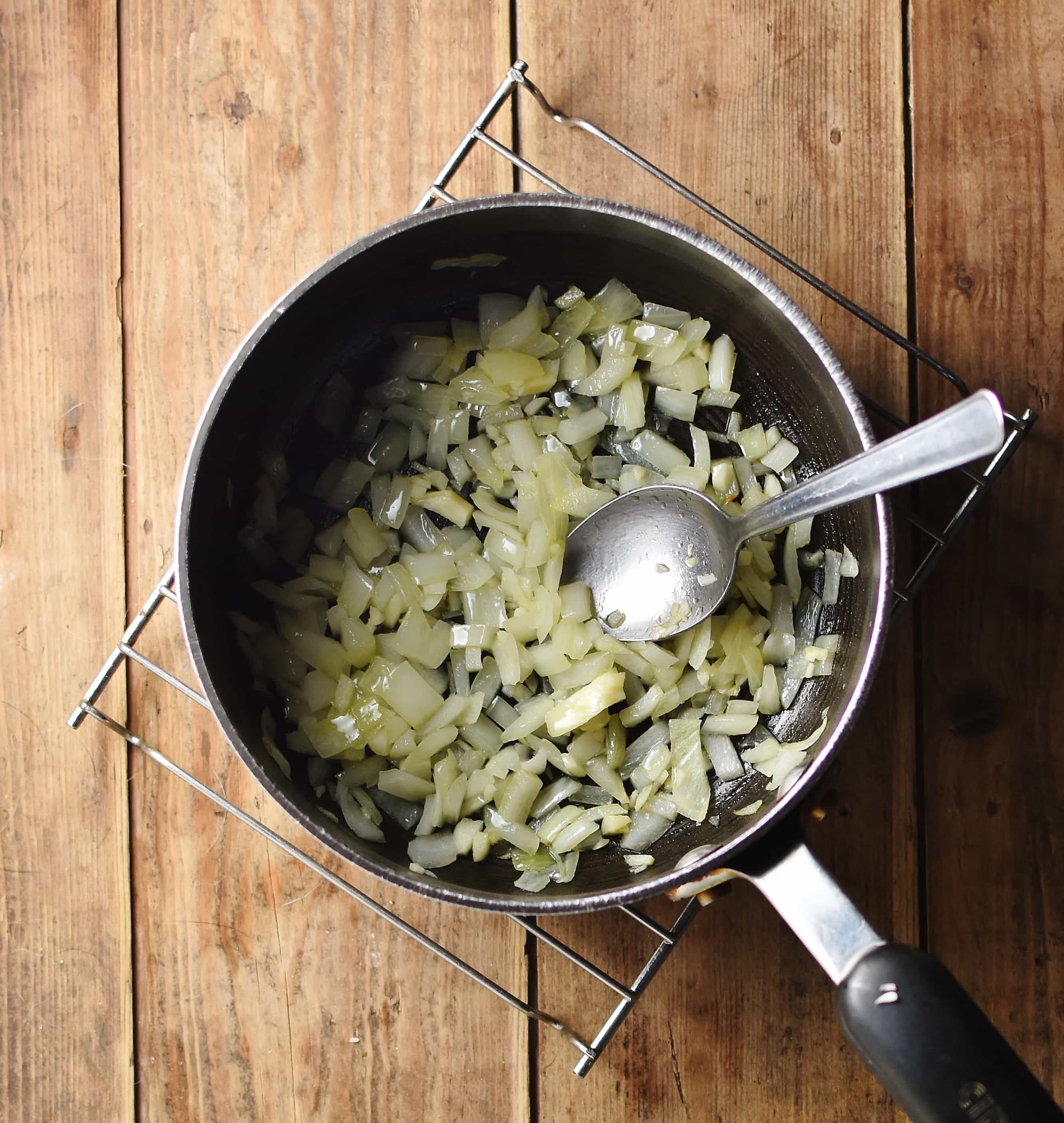 Chopped onion and spoon inside large pot on top of cooling rack.