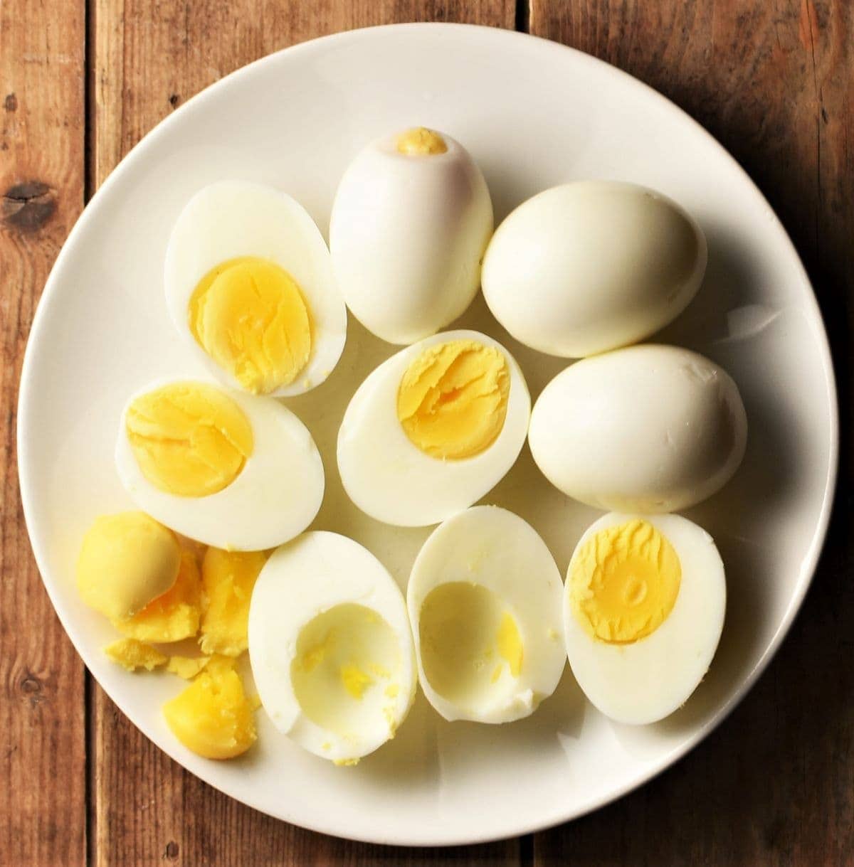 Halved hard boiled eggs on top of white plate.