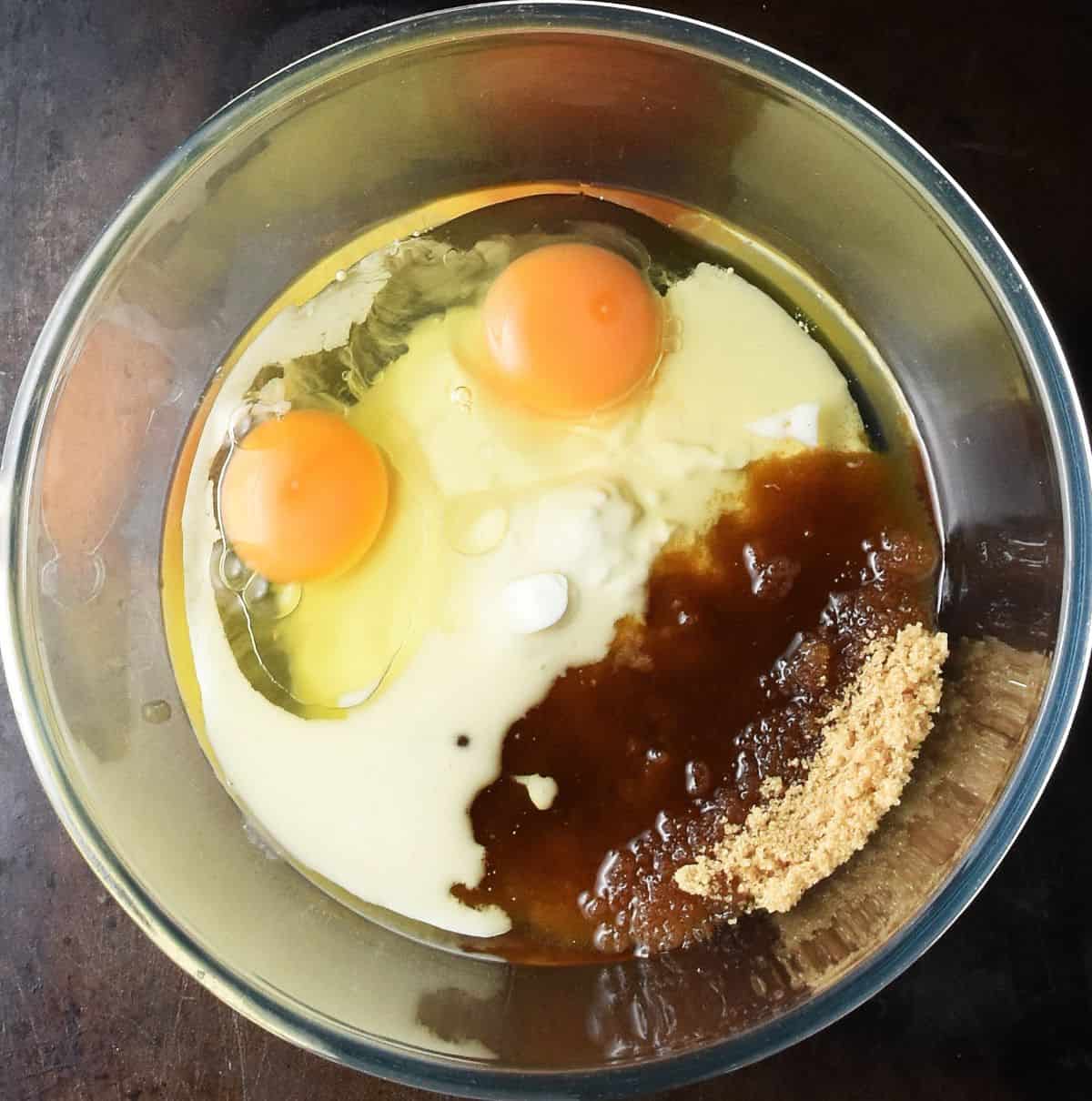 2 eggs, yogurt, oil and brown sugar in glass bowl.