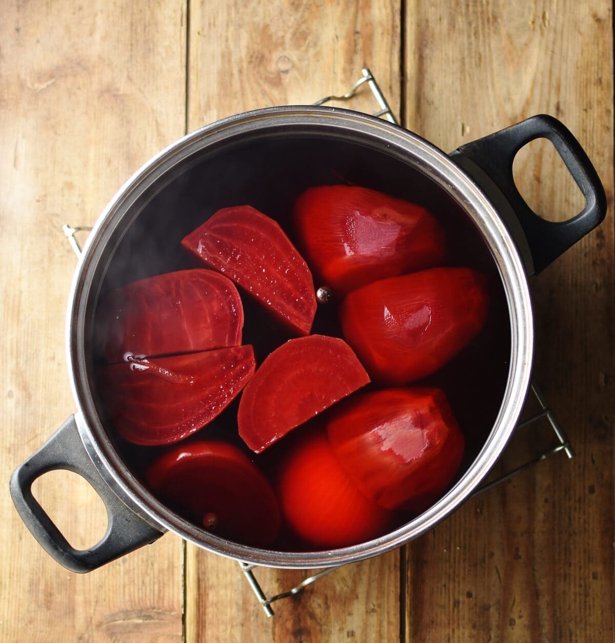 Pieces of beetroot inside large pot with water and steam coming out.