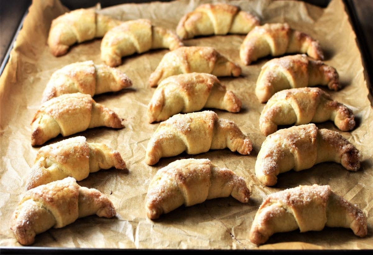Side view of baked crescent cookies on top of sheet.