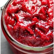 Close-up partial view of cranberry sauce inside open jar.
