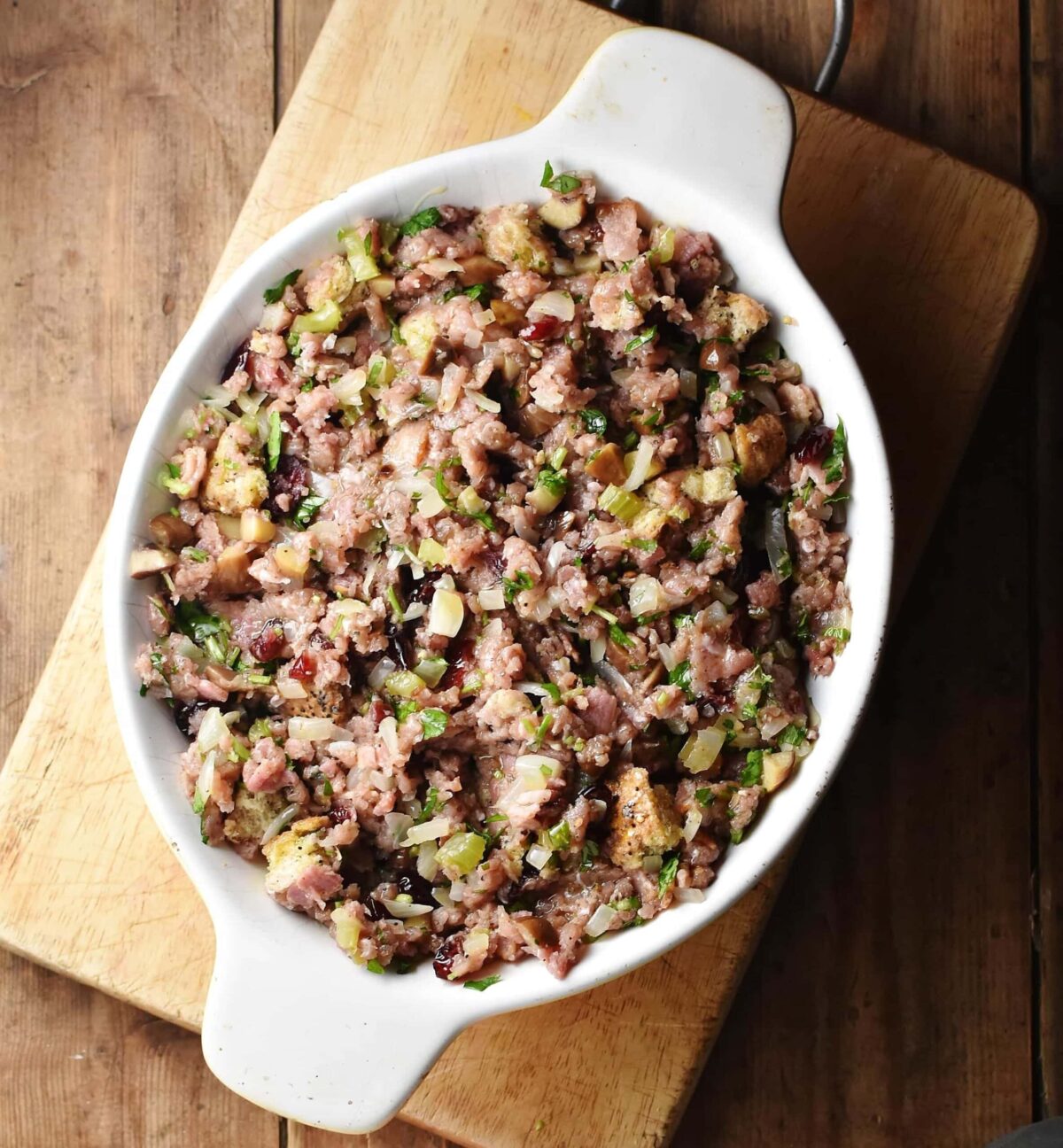 Turkey stuffing casserole in white oval dish on top of wooden board.