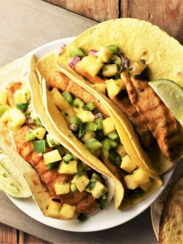 3 tortillas with chicken and pineapple salsa on plate.