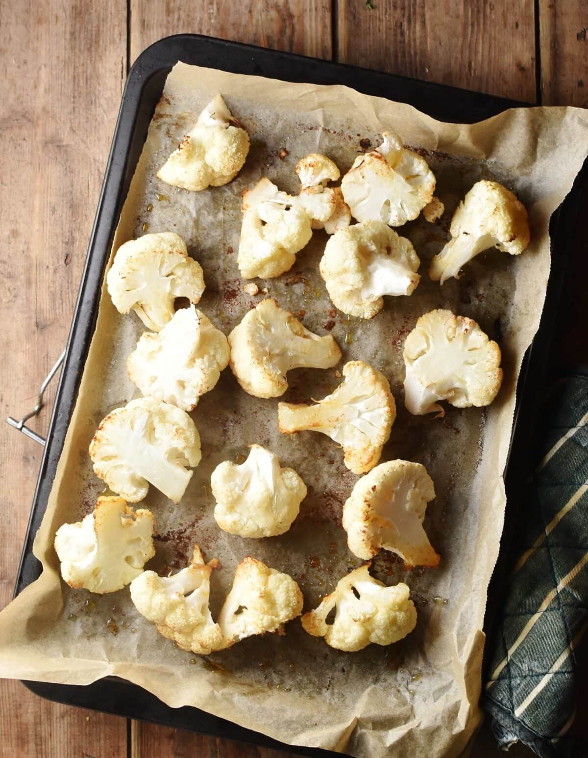 Roasted cauliflower florets on top of baking sheet lined with parchment paper. 